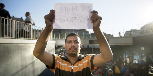 Ein Flüchtling in Budapest hält eine Papier hoch, auf dem er das Lager mit Guantanamo vergleicht