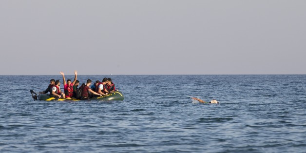 Migrants and refugees, one of them swims, arrive after crossing from Turkey, at the southeastern island of Kos, Greece, Monday, Aug. 17, 2015. With the lights of the Greek island of Kos twinkling through the darkness, beacons of hope for a new and better life, another group of migrants has come through this wealthy tourist town to make a risky, but less risky than most, sea crossing and apply for asylum in Europe. (AP Photo/Alexander Zemlianichenko)