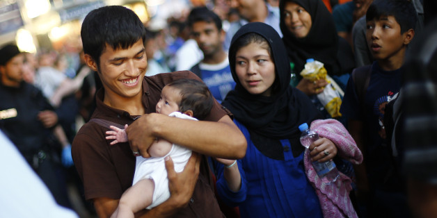 A man cradles a baby in his arms as migrants disembark from a train coming from Austria at the main station in Munich, Germany, Monday, Aug. 31, 2015. Some hundreds of migrants are arriving in Munich on Monday, after making perilous journeys into Europe. (AP Photo/Matthias Schrader)