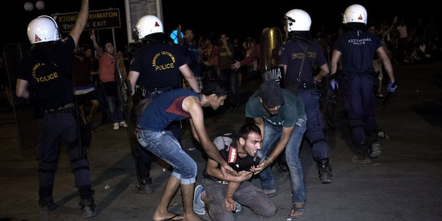 Migrants help another one to stand up during clashes with Greek police, while migrants try to board a ferry boat, in the port of Mytilene on the Greek Aegean island of Lesbos on September 5, 2015. More than 230,000 refugees and migrants arrived in Greece by sea this year, a huge rise from 17,500 in the same period in 2014, deputy shipping minister Nikos Zois said on September 3. AFP PHOTO / ANGELOS TZORTZINIS (Photo credit should read ANGELOS TZORTZINIS/AFP/Getty Images)