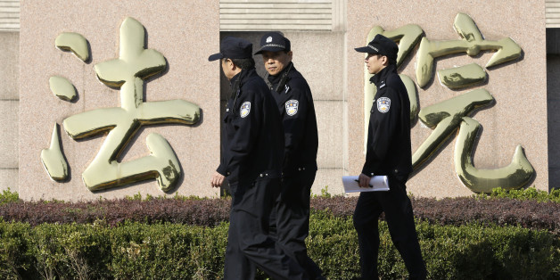 Policemen walk past Chinese characters reading "courthouse," (AP Photo/Alexander F. Yuan)