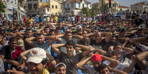 Refugees and migrants take part in a protest to demand faster processing by local authorities of their registration and the issuing of travel documents, at the port of Mytilene, on the northeastern Greek island of Lesbos, Monday, Sept. 7, 2015. Greece's caretaker government, appointed ahead of elections on Sept. 20, says at least two-thirds of the estimated 15,000 to 18,000 refugees and economic migrants stranded in "miserable" conditions on the Aegean island will be ferried to the mainland in t