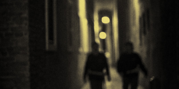 At night, a couple of police officers walk down the Calle Albanesi in Venice, Italy.
