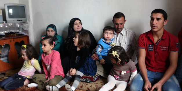 In this Thursday, Nov. 20, 2014 photo, Ahmad Aloun, 19, right, speaks during an interview with The Associated Press as he sits with his family at their house in the northern port city of Tripoli, Lebanon. The Alouns are one of several Syrian families who were given asylum in Uruguay after its government offered to accept 120 refugees. It's a small number compared to the 3 million Syrians who have fled the conflict, now in its fourth year, crowded into overwhelmed neighboring countries or who tri