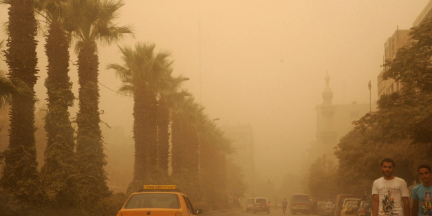 In this photo released by the Syrian official news agency SANA, Syrian citizens cross a street, as a sandstorm shrouds Damascus, Syria, Tuesday, Sept. 8, 2015. The unseasonal sandstorm hit Lebanon and Syria, reducing visibility and sending dozens to hospitals with breathing difficulties because of the fine dust. (SANA via AP)