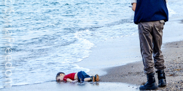 GRAPHIC CONTENTA Turkish police officer stands next to a migrant child's dead body off the shores in Bodrum, southern Turkey, on September 2, 2015 after a boat carrying refugees sank while reaching the Greek island of Kos. Thousands of refugees and migrants arrived in Athens on September 2, as Greek ministers held talks on the crisis, with Europe struggling to cope with the huge influx fleeing war and repression in the Middle East and Africa. AFP PHOTO / Nilufer Demir / DOGAN NEWS AGENCY