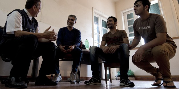 TO GO WITH AFP STORY by Laura Bonilla Priest Alex Coelho (L), of the Sao Joao Batista church, chats with Syrian refugees at an accommodation they were provided with by the church in Rio de Janeiro, on September 9, 2015. As Europe struggles to deal with hundreds of thousands of migrants fleeing bloody conflicts in Syria and beyond, far-away Latin America is increasingly stepping up pledges to take in refugees. Brazil, the largest Latin American country, has taken in more Syrian refugees than any