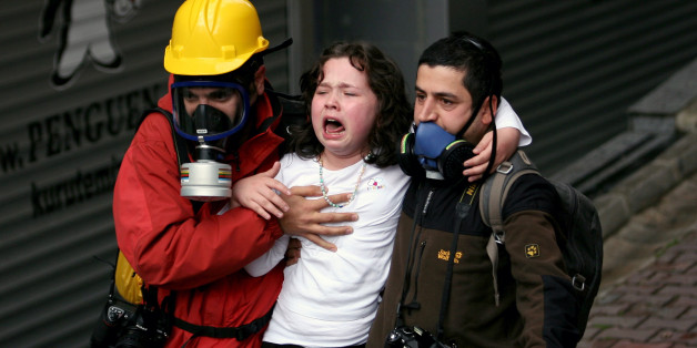 People help a child affected by teargas as riot police use water cannons and teargas to disperse thousands of people trying to reach the city's main Taksim Square to celebrate May Day in Istanbul, Turkey, Thursday, May 1, 2014. Clashes erupted between May Day demonstrators and riot police as crowds determined to defy a government ban tried to march to the city's iconic Taksim Square. Security forces pushed back demonstrators with water cannons and tear gas. (AP Photo/Emrah Gurel)