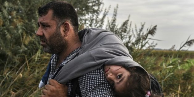 Un réfugié sa fille sur le dos le 14 septembre 2015 à Horgos en Serbie àla frontière avec la Hongrie