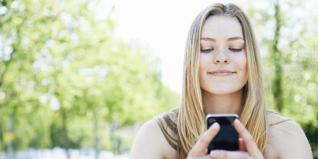 young woman smiling mobile phone in park