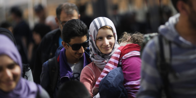 A woman with a baby, saying they are from Syria, arrives with other refugees at the train station of the southern German border town Passau, Tuesday, Sept. 15, 2015, after they have been taken off a train by German border police for registration. Germany introduced temporary border controls Sunday to stem the tide of thousands of refugees streaming across its frontier, sending a clear message to its European partners that it needs more help with an influx that is straining its ability to cope. (AP Photo/Markus Schreiber)