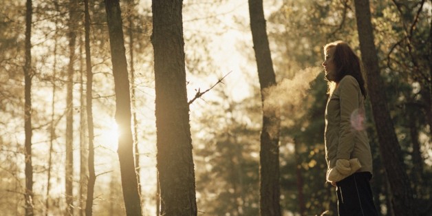 Side profile of a young woman standing in the forest