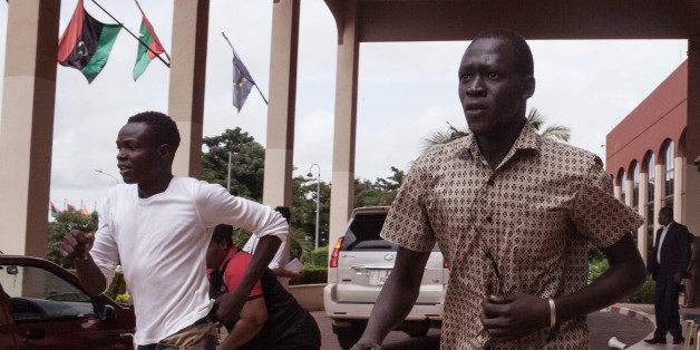 Anti coup protestors run away from the entrance to the Libya hotel where talks about the recent coup were taking place before soldiers arrived to disperse them in Ouagadougou, Burkina Faso, Sunday, Sept. 20, 2015. Violence broke out at the main hotel in Burkina Faso's capital on Sunday where talks were taking place with regional mediators as demonstrators opposed to last week's coup clashed with supporters of the military. (AP Photo/Theo Renaut)