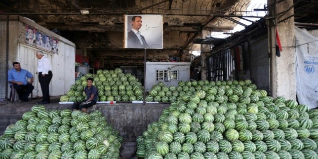 Des négociants syriens près du portrait du président Bachar al-Assad au marché des Halles de Damas, le 21 septembre 2015