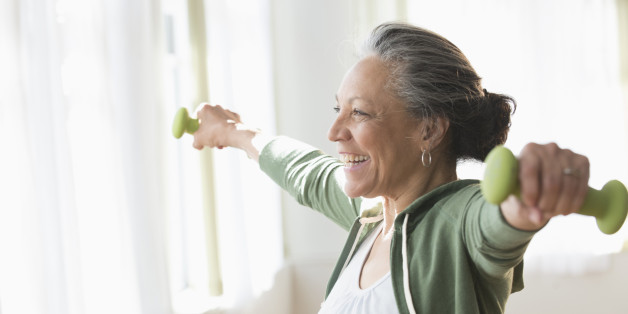 Older Hispanic woman lifting weights in living room