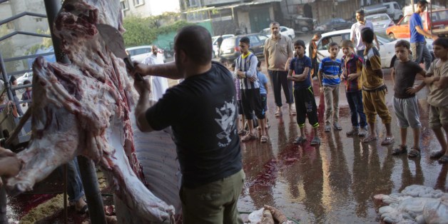 Palestinian children gather outside a butcher shop watch cows slaughtering in the first day of the Muslim holiday of Eid al-Adha, or Feast of Sacrifice, in Gaza City, Thursday, Sept. 24, 2015. Muslims all over the world celebrate the three-day festival Eid al-Adha, by sacrificing sheep, goats, camels and cows to commemorate the willingness of the Prophet Ibrahim (Abraham to Christians and Jews) to sacrifice his son, Ismail, on God's command. (AP Photo/ Khalil Hamra)