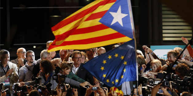 A "estelada" or pro independence flag and a European Union flag are waved in front of the President of Democratic Convergence of Catalonia Artur Mas, center in front of supporters in Barcelona, Spain, Sunday Sept. 27, 2015. Voters in Catalonia participated in an election Sunday that could propel the northeastern region toward independence from the rest of Spain or quell secessionism for years. An exit poll predicts that pro-independence parties in Spain's Catalonia region are likely to win a maj