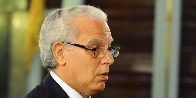New Tunisian Justice Minister Mohamed Salah Ben Aissa takes the oath of office with his hand resting on the Quran, during a ceremony in Tunis, Friday, Feb. 6, 2015. Prime Minister Essid, whose cabinet has ministers from four parties including the powerful Islamist group, promised "work and nothing but work" on the country's economic and security problems.(AP Photo/Hassene Dridi)