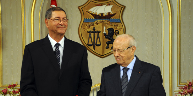 Habib Essid, 65, left, takes a document from newly elected Tunisian President Beji Caid Essebsi as he is asked to form a coalition and name a Cabinet over the next month, Monday, Jan.5, 2015 in Tunis. Tunisia's largest political party chose a veteran from the country's former dictatorship as its candidate for prime minister Monday and he began work immediately on forming a coalition government. (AP Photo/Hassene Dridi)