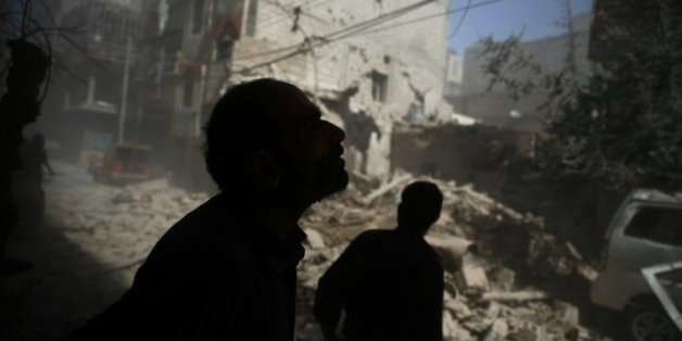 Des Syriens regardent les dégâts provoqués par des frappes aériennes sur la zone rebelle de Douma, à l'est de Damas, le 2 octobre 2015