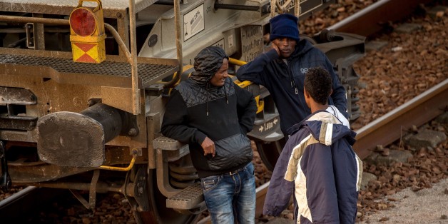 Migrants wait near a freight car on the railway tracks in Coquelles, near Calais northern France, before heading toward the Eurotunnel terminal on August 12, 2015. Some 3,000 migrants and refugees, including many fleeing war and persecution in countries like Syria, Libya and Eritrea, are camped out in a makeshift tent village in Calais waiting for a chance to cross to Britain. AFP PHOTO / PHILIPPE HUGUEN (Photo credit should read PHILIPPE HUGUEN/AFP/Getty Images)