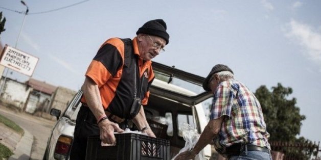 Adriaan Vlok (g), ancien ministre de l'apartheid, apporte de la nourriture au towsnhip d'Olievenhoutbosch, dans la banlieue de Pretoria, le 22 septembre 2015 en Afrique du Sud