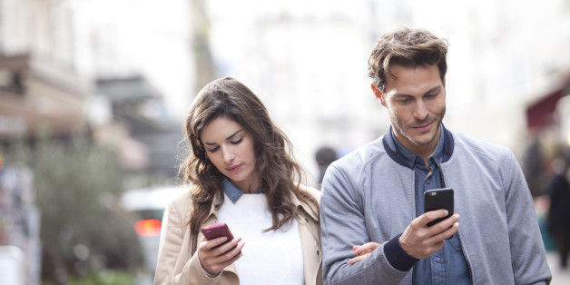 Couple walking in the street watching their phones