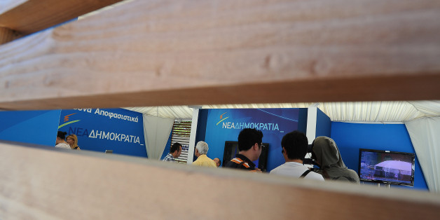 People walk inside a New Democracy conservative party election campaign kiosk near the Greek Parliament, in central Athens, on June 12, 2012. Pro-bailout or anti-austerity, whoever wins Greece's crunch election on June 17 will inherit an economy in tatters after two years of incomplete reforms and despite billions of euros in EU-IMF support. AFP PHOTO / ANDREAS SOLARO (Photo credit should read ANDREAS SOLARO/AFP/GettyImages)