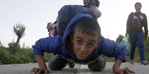 A migrant boy jokes with the photographer whilst heading to cross the border between Serbia and Croatia, near the village of Berkasovo, about 100 km west from Belgrade, Serbia, Tuesday, Sept. 22, 2015. Serbia's prime minister Aleksandar Vucic said Tuesday that Croatia's closure of the main border crossing for cargo trucks early Monday is "a scandal of international proportions."(AP Photo/Darko Vojinovic)