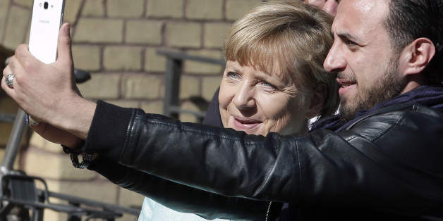 An unidentified man takes a picture of himself and German Chancellor Angela Merkel, left, during Merkel's visit at a registration center for migrants and refugees in Berlin, Germany, Thursday, Sept. 10, 2015. (AP Photo/Michael Sohn)