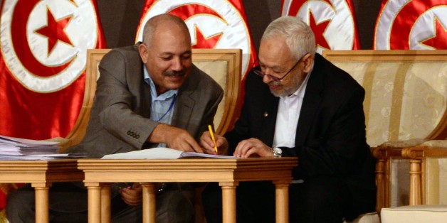 In this photo taken Saturday, Oct. 5, 2013, Tunisia's ruling Islamist Ennahda party leader Rached El Ghannouchi, right, signs documents during a meeting as part of the dialogue between Tunisia's ruling Islamists and the opposition at the Palais des Congres, in Tunis. Nearly all of Tunisia's feuding political parties on Saturday signed on to a roadmap designed to break their months-old impasse and put an end to the country's drawn-out democratic transition. (AP Photo/ Hassene Dridi)