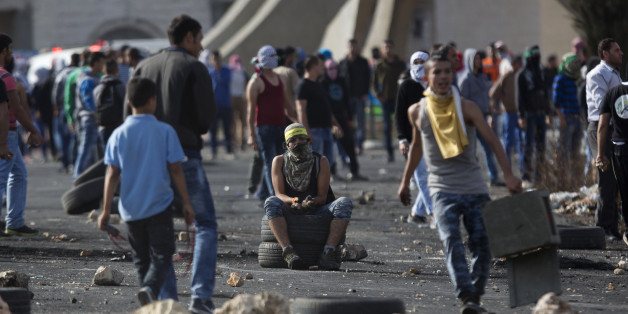 A Palestinian protester sits on tires during clashes with Israeli troops near Ramallah, West Bank, Thursday, Oct. 8, 2015. Dozens of Palestinian protesters threw stones at Israeli troops near the West Bank city of Ramallah and elsewhere on Thursday. Israeli forces responded with tear gas and stun grenades. (AP Photo/Majdi Mohammed)