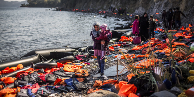 SKALA SIKAMINIAS, GREECE - OCTOBER 04: A woman carries her child as she arrives with other refugees on the shores of the Greek island of Lesbos after crossing the Aegean sea from Turkey on an inflatable boat on October 4, 2015 near village of Skala Sikaminias, Greece. Despite bad weather due to the upcoming Autumn, migrants and refugees are risking their lives in search of a better one in the European Union. Officals have warned that a rise in migrant deaths is expected as weather conditions gradually worsen. (Photo by Matej Divizna/Getty Images)