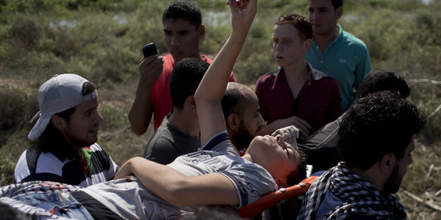 Palestinians carry a wounded man during clashes with Israeli soldiers on the Israeli border of Gaza City on Friday, Oct. 9, 2015. Unrest that erupted several weeks earlier at Jerusalem's most sensitive holy site spread Friday to Gaza in the form of deadly border clashes with Palestinian protesters, as Israeli security forces struggled to contain a wave of Palestinian stabbing attacks against civilians and soldiers. (AP Photo/ Khalil Hamra)