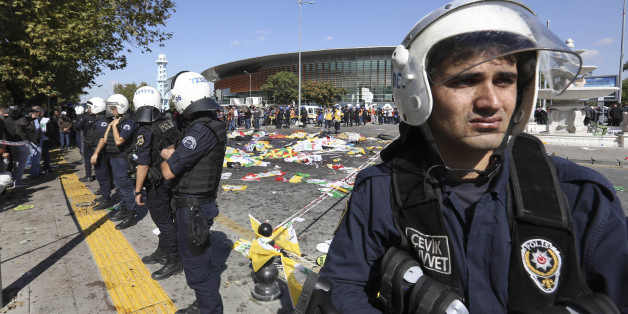 Turkish police officers secure the area at the site of an explosion, where the bodies of victims were covered with flags and banners, in Ankara, Turkey, Saturday, Oct. 10, 2015. The two bomb explosions targeting a peace rally in the capital Ankara has killed dozens of people and injured scores of others. The explosions occurred minutes apart near Ankara's main train station as people were gathering for the rally, organized by the country's public sector workers' trade union and other civic soci