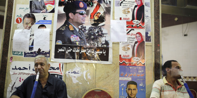 Egyptians smoke traditional "Shisha", water pipe, under a poster of President Abdel-Fattah el-Sissi, centre, with Arabic that reads, "Viva Egypt", and posters with pictures of parliamentary candidates, ahead of parliamentary elections next week. (AP Photo/Amr Nabil)