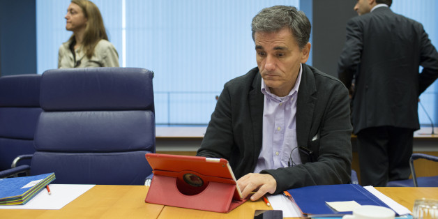 Euclid Tsakalotos, Greece's finance minister, looks at Apple Inc. iPad tablet device ahead of roundtable talks during a Eurogroup meeting in Luxembourg, on Monday, Oct. 5, 2015. French Finance Minister Michel Sapin said Greece needs to make good on its promises with euro-area lenders as soon as possible so the creditors can move on to discuss easing the country's debt burden. Photographer: Jasper Juinen/Bloomberg via Getty Images
