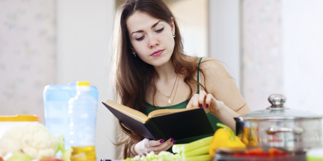thoughtful girl cooking with cookbook in the kitchen at home