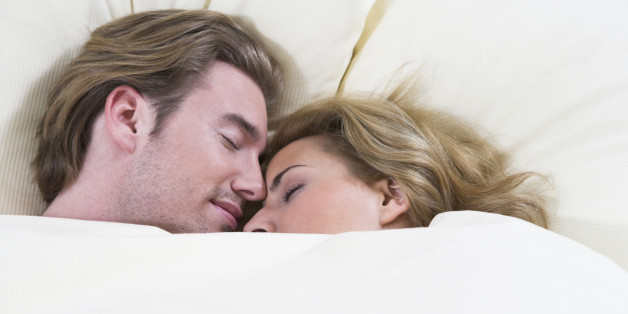 headshot of young couple sleeping closely together in bed