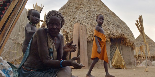 TO GO WITH AFP STORY BY AYMERIC VINCENOT An elderly woman sits on the ground outside a hut on one of a handful of habitable islands that dot the Sudd swamp just off the shores of Nyal, an administrative hub in Unity state, South Sudan where scores now face starvation after their farms were inundated by rising waters from the nearby swamp, on February 24, 2015. AFP PHOTO/TONY KARUMBA (Photo credit should read TONY KARUMBA/AFP/Getty Images)