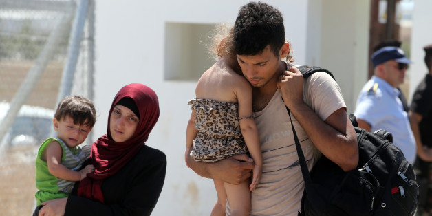 Migrants carrying children arrive at a camp after they were rescued by authorities in the Mediterranean Sea near Larnaca, in Kokkinotrimithia, Cyprus, Sunday, Sept. 6, 2015. Cypriot authorities said Sunday they rescued 114 people believed to be refugees fleeing war-torn Syria after their fishing boat issued a distress call some 46 miles (74 kilometers) off the eastern Mediterranean island nationâs southern coast. (AP Photo/Philippos Christou)