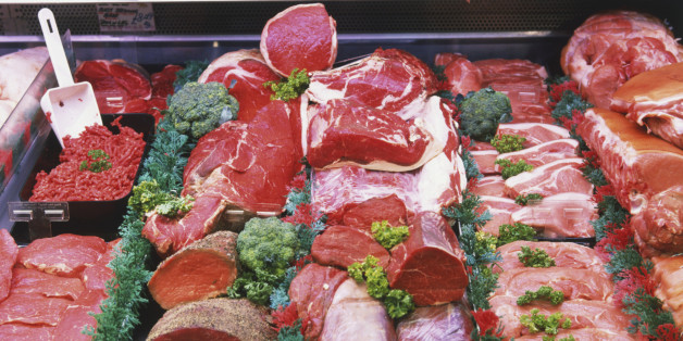 Red meats with herb garnish on display at meat counter