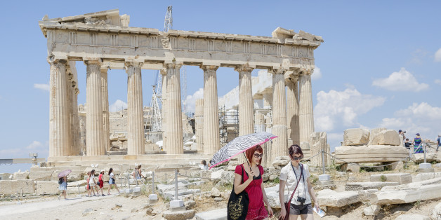 Tourists walk trough the ancient Acropolis hill, with the ruins of the fifth century BC Parthenon temple on the background in Athens, Monday, June 29, 2015. Anxious Greeks lined up at ATMs as they gradually began dispensing cash again on the first day of capital controls imposed in a dramatic twist in Greece's five-year financial saga. Banks will remain shut until next Monday, and a daily limit of 60 euros ($67) has been placed on cash withdrawals from ATMs. (AP Photo/Daniel Ochoa de Olza)