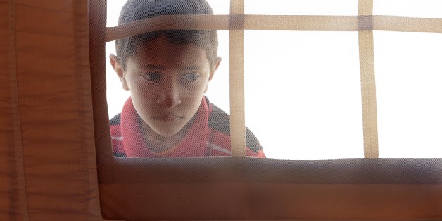 A Libyan child peers into the window of a tent in the U.A.E. Red Crescent refugee camp at the Tunisian village of Dhuheiba, Friday, April 22, 2011. In recent weeks, more than 10,000 Libyans from the border region had crossed into Tunisia, and 1,200 found shelter in a tent camp near the village of Dhuheiba, a few miles from the border. (AP Photo/Pier Paolo Cito)