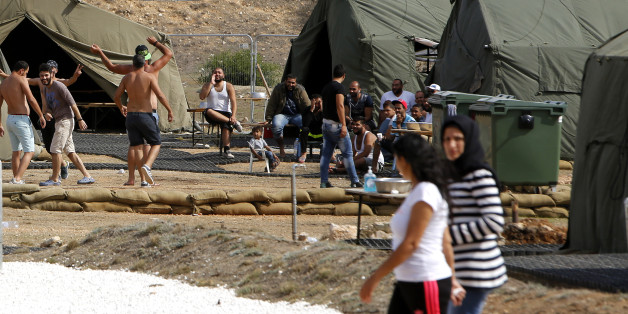 Migrants are seen at the temporary transit facility in Dhekelia Garrison, a British military base on the east Mediterranean island of Cyprus on Wednesday, Oct. 28, 2015. The base's authorities said 114 people whose fishing boats landed on the shore of another British base on Cyprusâ southern coast last week have been transferred to Dhekelia where they will be provided with âmore suitable accommodation. â British authorities insist the bases, which are considered sovereign territor
