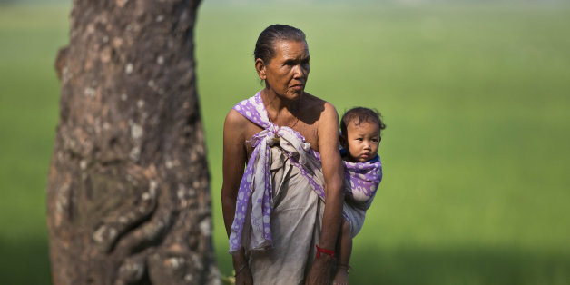 An elderly woman carries a child on her back as she stands near a paddy field in Hahara village, about 65 kilometers (40 miles) east of Gauhati, India, Saturday, Sept. 26, 2015. Indian Prime Minister Narendra Modi addressed the U.N. General Assembly saying eliminating poverty is the top priority in his country, which has the worldâs largest number of people living in extreme poverty. (AP Photo/Anupam Nath)