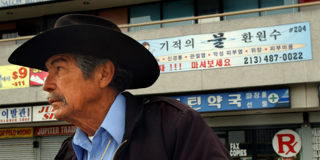 Guadalupe Saldivar, who is unemployed and lives with friends, sits in front of a strip mall with Korean writing on it in the Koreatown section of Los Angeles, Saturday, April 23, 2005. Koreatown is enjoying a renaissance 13 years after riots destroyed many of its businesses, but beneath the facelift an increasing economic divide could threaten its stability, activists said Saturday. (AP Photo/Ann Johansson)