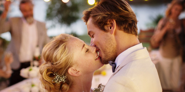 Young couple kissing during wedding reception in domestic garden