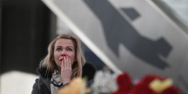 A woman reacts at an entrance of Pulkovo airport during a day of national mourning for the victims of the plane crash, outside St. Petersburg, Russia, Tuesday, Nov. 3, 2015. In a massive outpouring of grief, thousands of people flocked to St. Petersburg's airport, laying flowers, soft toys and paper planes next to the pictures of the victims of the crash of a passenger jet in Egypt that killed all 224 on board in Russia's deadliest air crash to date. (AP Photo/Dmitry Lovetsky)