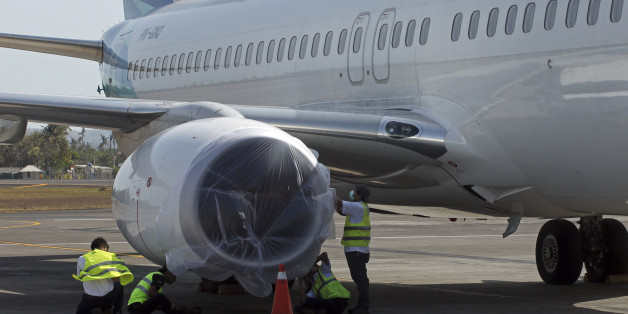 Workers cover a plane engine with a plastic sheet in their attempt not to be damaged by volcanic ash at Ngurah Rai International Airport in Bali, Indonesia on Wednesday, Nov. 4, 2015. Thousands of tourists are stranded on three Indonesian islands after ash from the Mount Rinjani volcano forced the closure of airports and blanketed villages and farmlands. The eruption shut down flights at the Ngurah Rai international airport in Bali, about 135 kilometers (84 miles) from Lombok, and the Selaparang